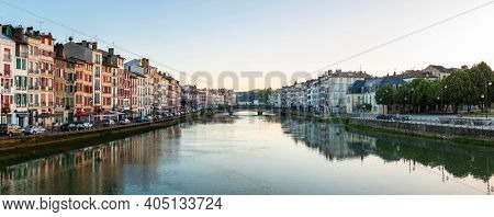 Panoramic view of Bayonne and the Nive River at sunrise in the French Basque Country, France. Old colorful facades and their reflection on the water surface.