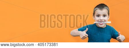 Boy Without Milk Upper Tooth In Blue T-shirt Holds Toothbrush In His Mouth On The Orange Background.