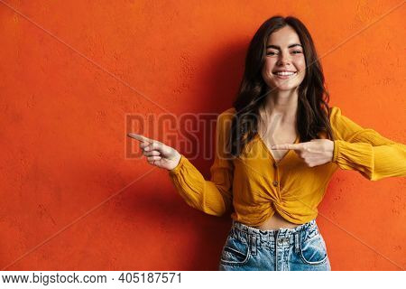 Portrait of cheerful young woman prsenting copy space while standing over isolated background