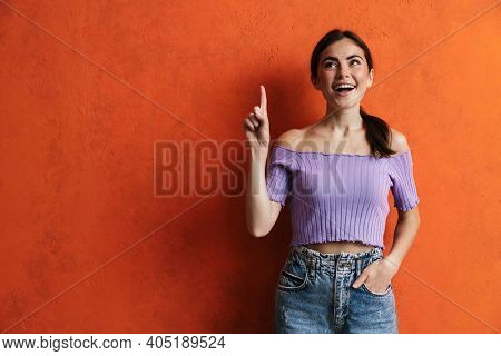 Portrait of cheerful young woman prsenting copy space while standing over isolated background