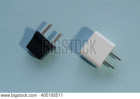 Black And White Interchangeable Dc And Ac Plugs. Wall Adapters For Usa And Europe On Blue Background