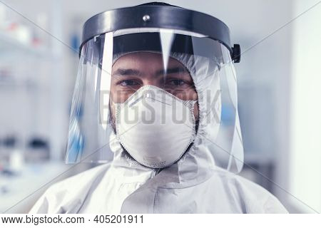 Tired Healthcare Scientist Loooking At Camera Wearing Ppe Suit With Face Shieldin Lab. Overworked Re