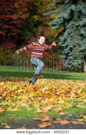 Boy Playing In Fall Leaves