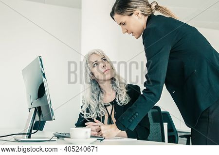Project Manager Affixing Signature On Employees Report. Female Business Colleagues Sitting And Stand