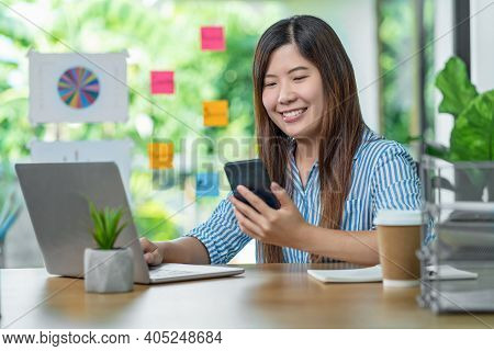 Asian Businesswoman Using Mobile Phone And Working With Laptop In Indoor Living Room, Work At Home C