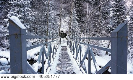 First-person View Of A Metal Bridge In The Forest. I Walk Across A Bridge In A Snowy Gorge, Among Wh