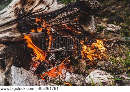 Kettle Hanging Over Fire. Cooking Food At Fire In Wild. Beautiful Big Log Burns In Bonfire Close-up.