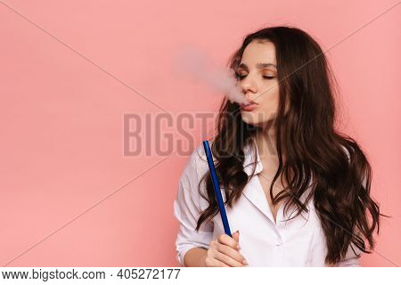 Young Woman Smokes A Hookah, Sheesha On A Pink Background. The Pleasure Of Smoking.