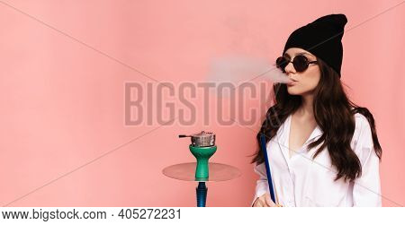 A Young Woman In A Hipster Image Smokes A Hookah, Sheesha And Enjoys Smoking. Place For Your Text.