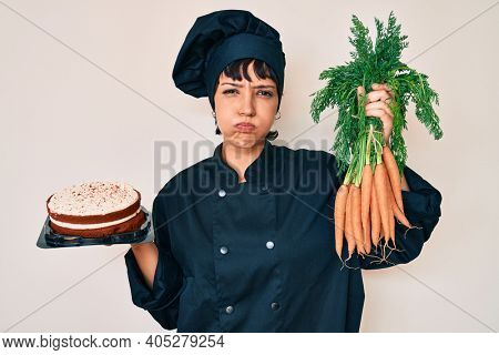 Beautiful brunettte woman chef cooking carrot cake puffing cheeks with funny face. mouth inflated with air, catching air. 