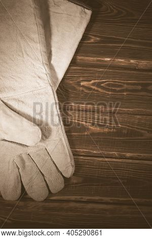 White Leather Welder Gloves On A Wooden Background. A Studio Photo With Hard Lighting.