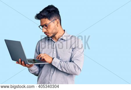 Handsome latin american young man working using computer laptop thinking attitude and sober expression looking self confident 