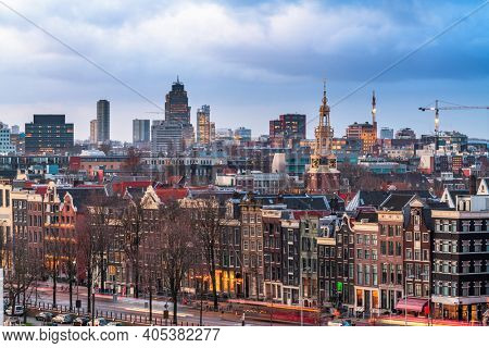 Amsterdam, Netherlands historic cityscape with the modern Zuidas district in the distance at dusk.