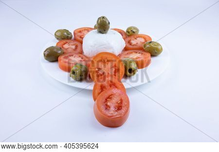 The Meal On A White Plate On A White Background Consists Of Sliced Tomatoes, Pitted Olives And Mozza