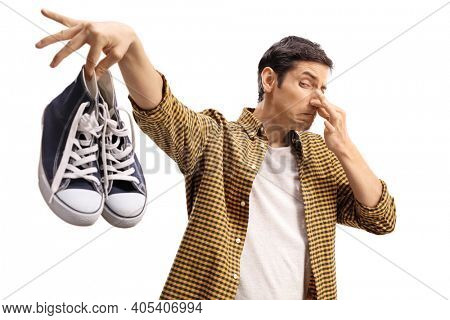 Guy holding a pair of smelly trainers isolated on white background