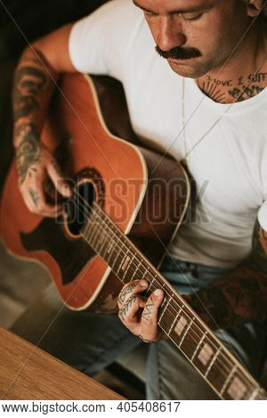 Tattooed singer songwriter playing an acoustic guitar
