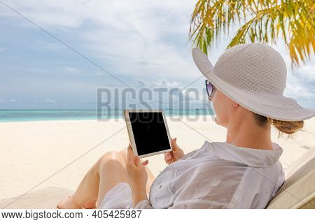 Young Woman In Hat With Tablet Pc At The Beach. Remote Work On Beautiful Beach Landscape View. Blank