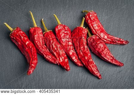 Red Pepper. Dry Peppers Are Spread Out On A Black Slate Stone. Hot Chili Peppers. Spices For Cooking
