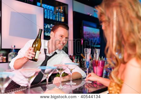 若い女性のクラブやバーはシャンペンを飲んで、バーの主人と気を惹く