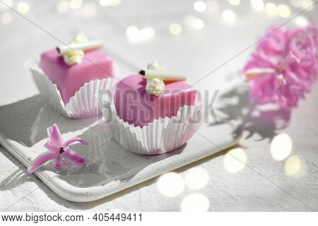 Valentine Petit Fours With Marzipan Icing. Fragrant Pink Hyacinth Flower. Garland Of Lights On White