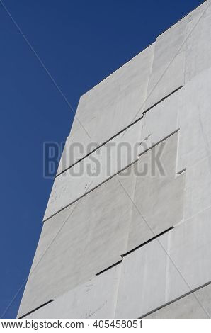 A Fragment Of A Tall Residential Building Against A Clear Blue Sky. A White Apartment Building. View