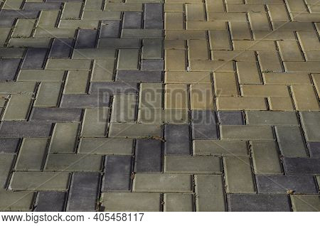 Colorful Cobblestone Pavement. Tri-color Stone Paving With Fallen Leaves And Sprouting Green Grass