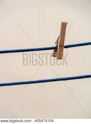 One Wooden Clothespin On A Blue Rope With Hanging Waterdrops After The Rain On Blurred Background.