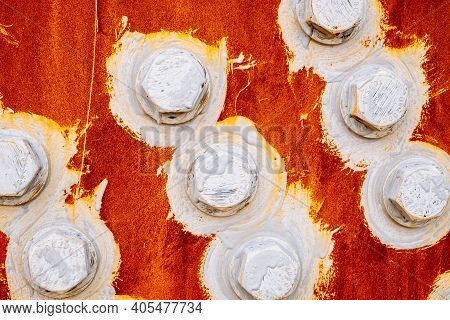 Abstract Background Of Bolts And Nuts Painted White On A Red Background