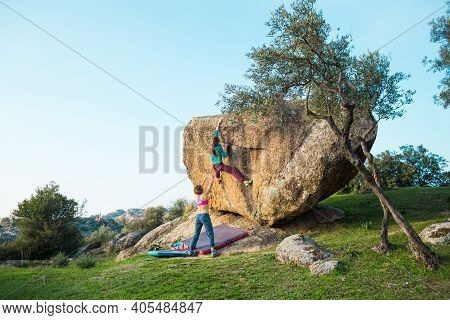 Two Young Girls Climb Bouldering Outdoors. Rock Climber Climbs A Difficult Route. Do Sports Outside 