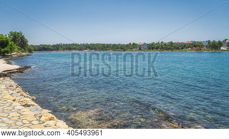 People Relaxing In Clear Waters Of Zaton Bay With Rocky Coastline. Families Having Fun In Turquoise 