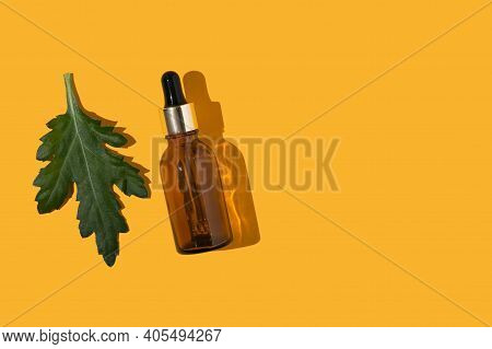 Dropper Bottle And A Green Leaf On The Ochre Backrgound With The Empty Space For Text Place