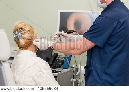 Ent Doctor With Tools Wearing Mask And Gloves Examines The Patients Ear. Otolaryngologist Doing Otit