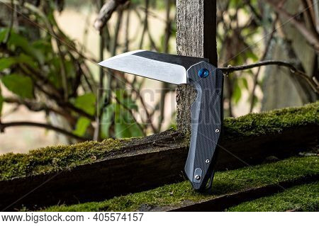 A Sharp Knife In A Bent Position. Knife On The Background Of A Bush. Daylight