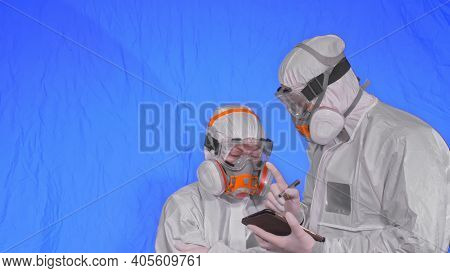 Scientist Virologist In Respirator Makes Write In An Tablet Computer With Stylus. Man And Woman Wear