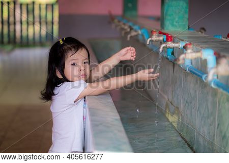 Asian Baby Little Girl Is Trying To Stretch To Wash Her Hands With A Faucet That Is A Little Higher 
