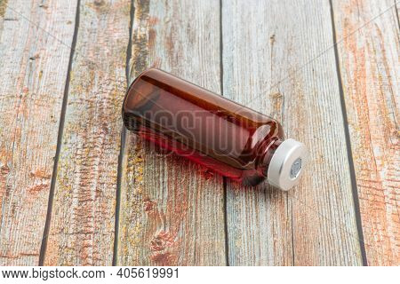A Macro Shot With Selective Focus Of An Amber Color Vaccine Injection Vial Set On A Wood Background.