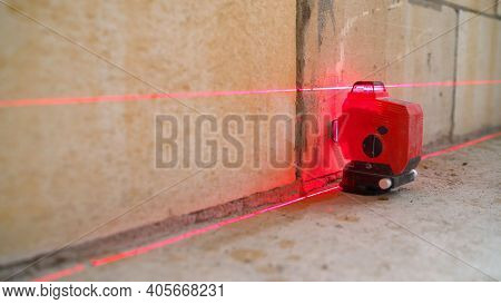 The Construction Laser Level Is On The Floor. The Beam Is Directed At The Wall. Aligning The Walls W