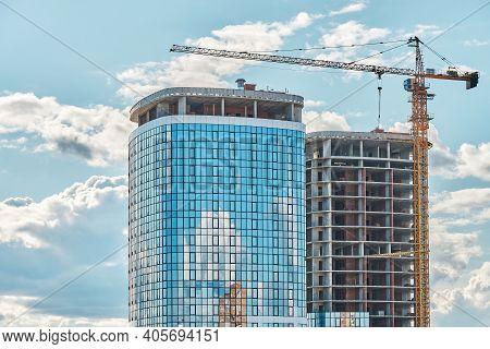 Crane Near Skyscraper With Glass Facade At Construction Site
