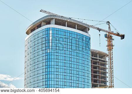Crane Near Skyscraper With Glass Facade At Construction Site