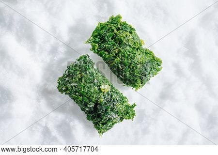 Two Frozen Parsley Green Briquettes On A Grinded Ice. Top View.