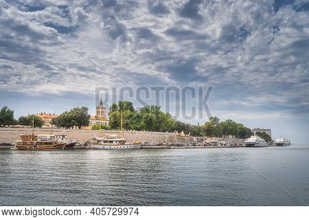 Pier With Moored Sailboats And Ferries In Zadar Bay. Fortification, Walled Old Town And Belltower Of