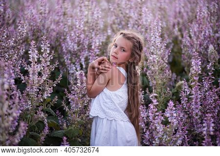 Close-up Portraits Of A Little Girl With Long Flowing Hair In Blooming Pink Sage Field. Dreamer Blon