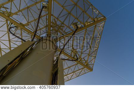Low Angle View Of Grid Support Of Large Electrical Tower With Sun Shining From Behind Tower.
