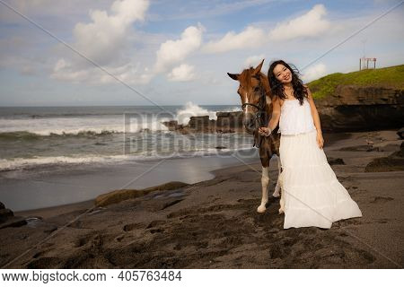 Smiling Woman Leading Horse By Its Reins. Horse Riding On The Beach. Human And Animals Relationship.