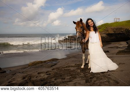 Happy Woman Leading Horse By Its Reins. Horse Riding On The Beach. Human And Animals Relationship. A