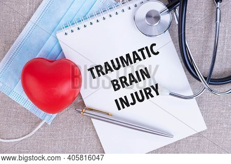 Traumatic Brain Injury, The Text Is Written In A Notebook, Next To A Pen, A Disposable Medical Mask