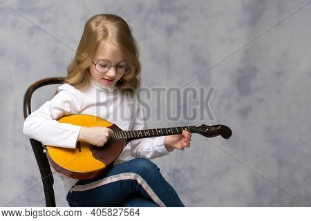 Cute Little Girl Learning To Play The Plucked Musical Instrument, Domra.