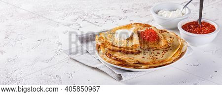 Traditional Russian Crepes Blini Stacked In A Plate With Red Caviar, Fresh Sour Cream On Light Backg