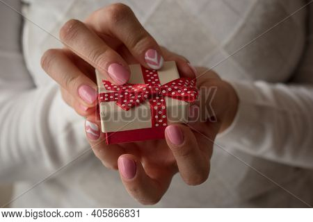 Woman Hands Holding A Small Present Box With Red Ribbon Over. Valentine Gift Box. Close Up Shot Of F