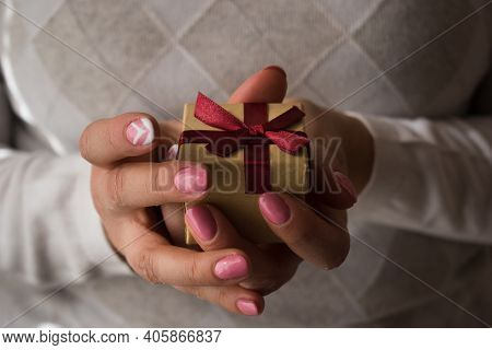 Woman Hands Holding A Small Present Box With Red Ribbon Over. Valentine Gift Box. Close Up Shot Of F